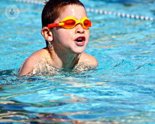 Niño nadando en una piscina con boca abierta respirar por la boca