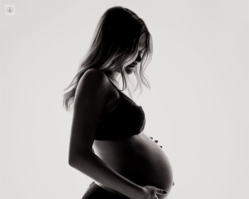 Chica de perfil, mostrando la tripa con embarazo avanzado - como aliviar el dolor en el parto - by Top Doctors