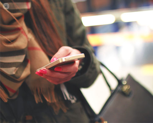 Primer plano de una chica con el móvil en la mano - TOC y redes sociales by Top Doctors