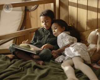 niños en la cama mirando un libro juntos