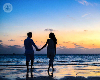 pareja pasea junta por la orilla de la playa en puesta de sol