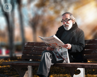 hombre mayor leyendo el periódico en un banco