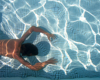 hombre bajo el agua de la piscina en verano