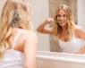 mujer lavandose los dientes frente al espejo