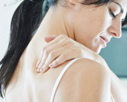 Chica tocándose la espalda con dolor - fisioterapia láser - lesiones by Top Doctors