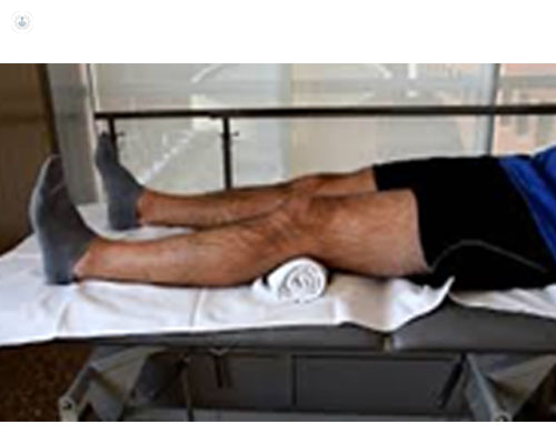 Paciente tumbado boca arriba, con una toalla debajo de la rodilla - rehabilitación COVID-19
