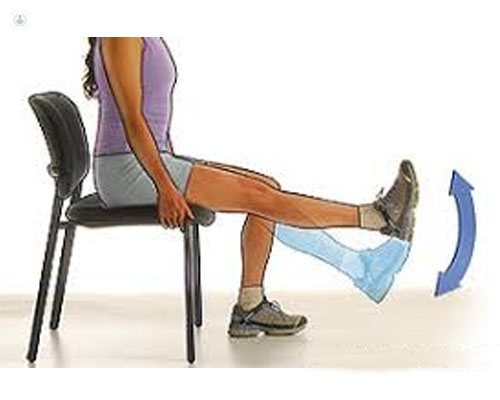 Chica sentada en una silla, levantando la pierna - COVID-19 - by Top Doctors