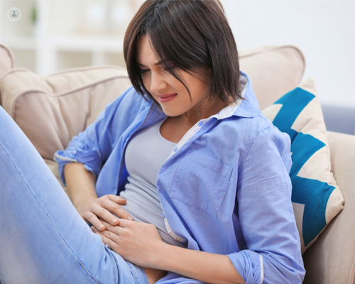 Mujer sentada tocándose el bajo vientre - pólipos endometriales by Top Doctors