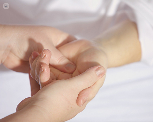 Primer plano de unas manos, una persona agarrando la mano de otra - síndrome del túnel carpiano - by Top Doctors