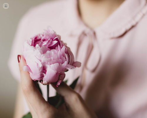 Primer plano de una mujer con una flor en la mano - VPH y Ginecología - by Top Doctors