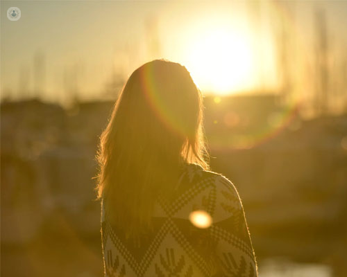 Chica de espaldas, mirando al infinito, en una puesta de sol - introspección y conocerse a uno mismo - by Top Doctors