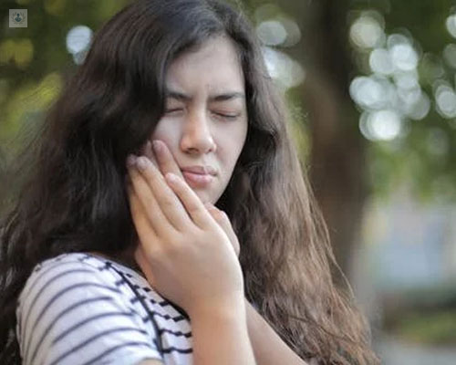 Chica tocándose la mandíbula en actitud de dolor - bruxismo y trastornos ATM - by Top Doctors