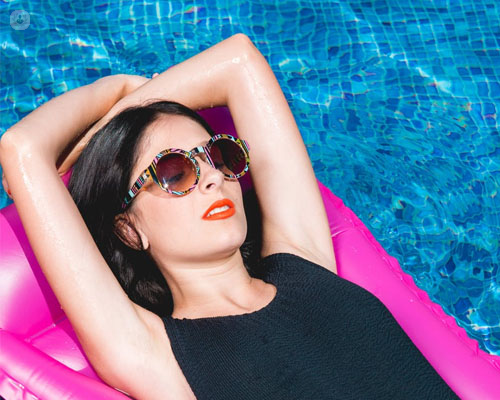 Chica en una colchoneta en la piscina con gafas de sol - oftalmología verano by Top Doctors