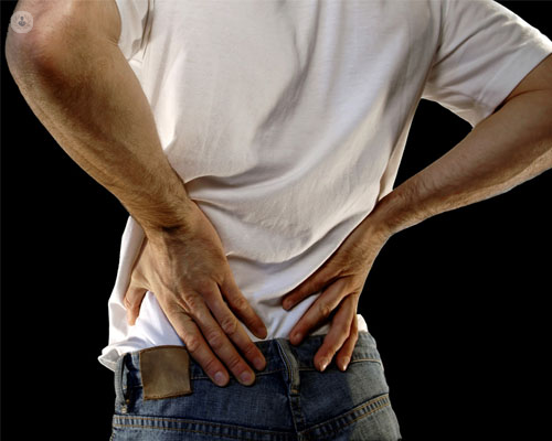 Persona agarrándose las lumbares con dolor - ciática y hernia - by Top Doctors