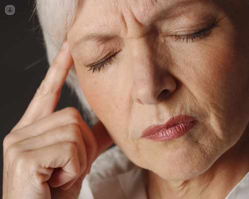 Mujer sosteniéndose la cabeza en actitud pensativa - Alzheimer y demencia by Top Doctors