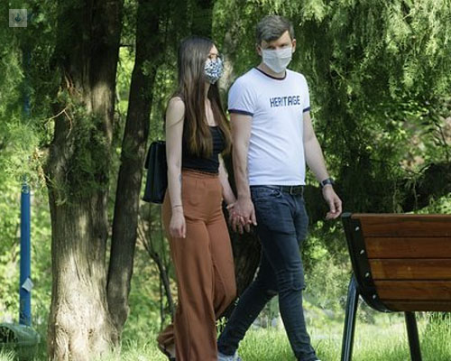 Pareja paseando por un parque con mascarillas - deconfinamiento COVID-19 - by Top Doctors