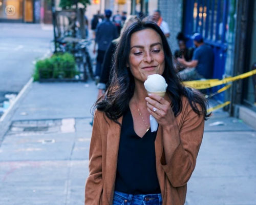 Chica comiendo un helado en la calle - sensibilidad dental by Top Doctors