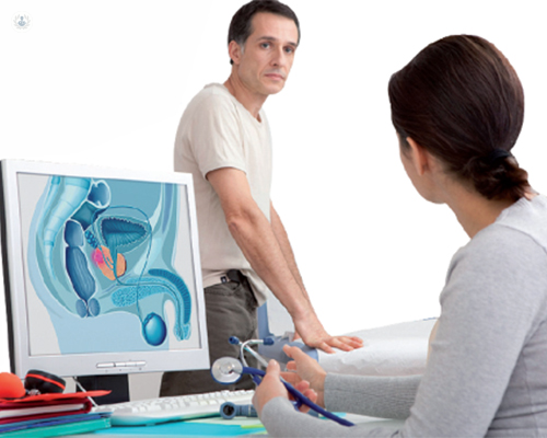 Hombre y doctora en consulta, ante un ordenador con imagen de aparato reproductivo urinario masculino - cancer de prostata - urologia - by Top Doctors