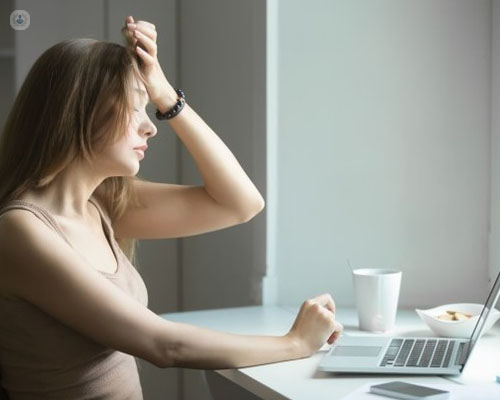 Chica con actitud de estrés y ansiedad delante de un ordenador - ansiedad - by Top Doctors