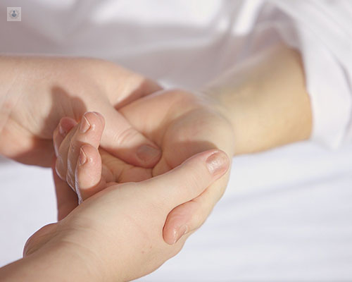 Primer plano de unas manos, doctor tocando la palma y muñeca de una paciente - síndrome del túnel carpiano - by Top Doctors