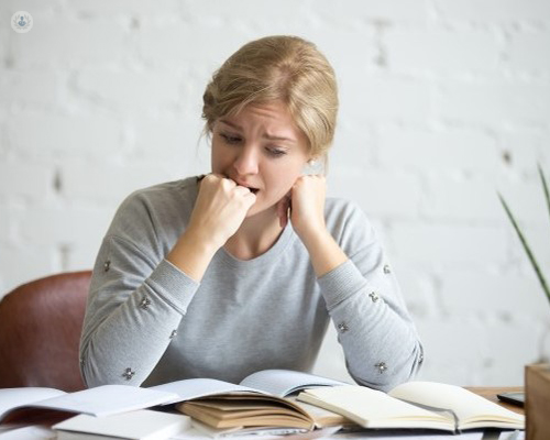 Foto de una chica estresada mirando a unos libros - ansiedad y estrés - by Top Doctors