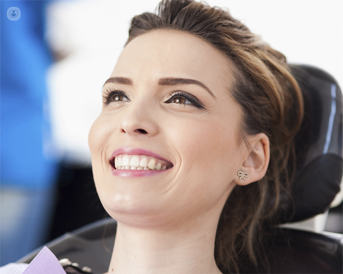 Chica sentada en camilla mostrando los dientes, sonriendo - implantes de carga inmediata by Top Doctors