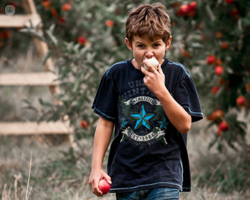 Niño comiendo una manzana con cara de enfado - epilepsia en niños y dieta cetogénica by Top Doctors