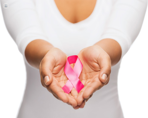 Primer plano de unas manos de mujer sosteniendo un lazo rosa - Día Mundial contra el Cáncer de Mama - by Top Doctors