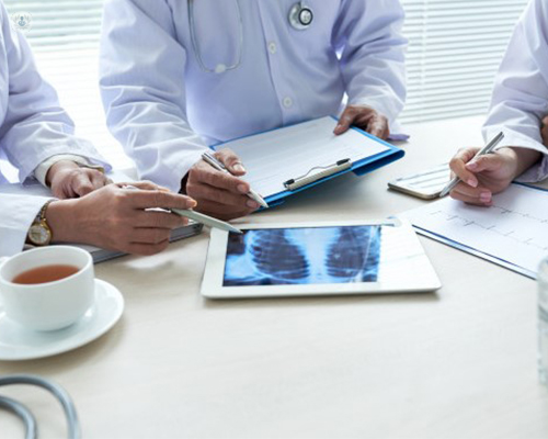 Doctores reunidos mostrando una radiografía del tórax de un paciente - radiocirugía estereotáxica - by Top Doctors